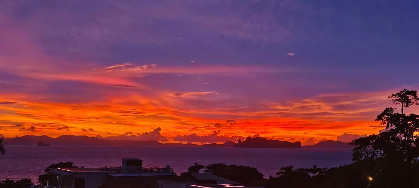 A red and orange sunset over the sea, limestone islands on the horizon